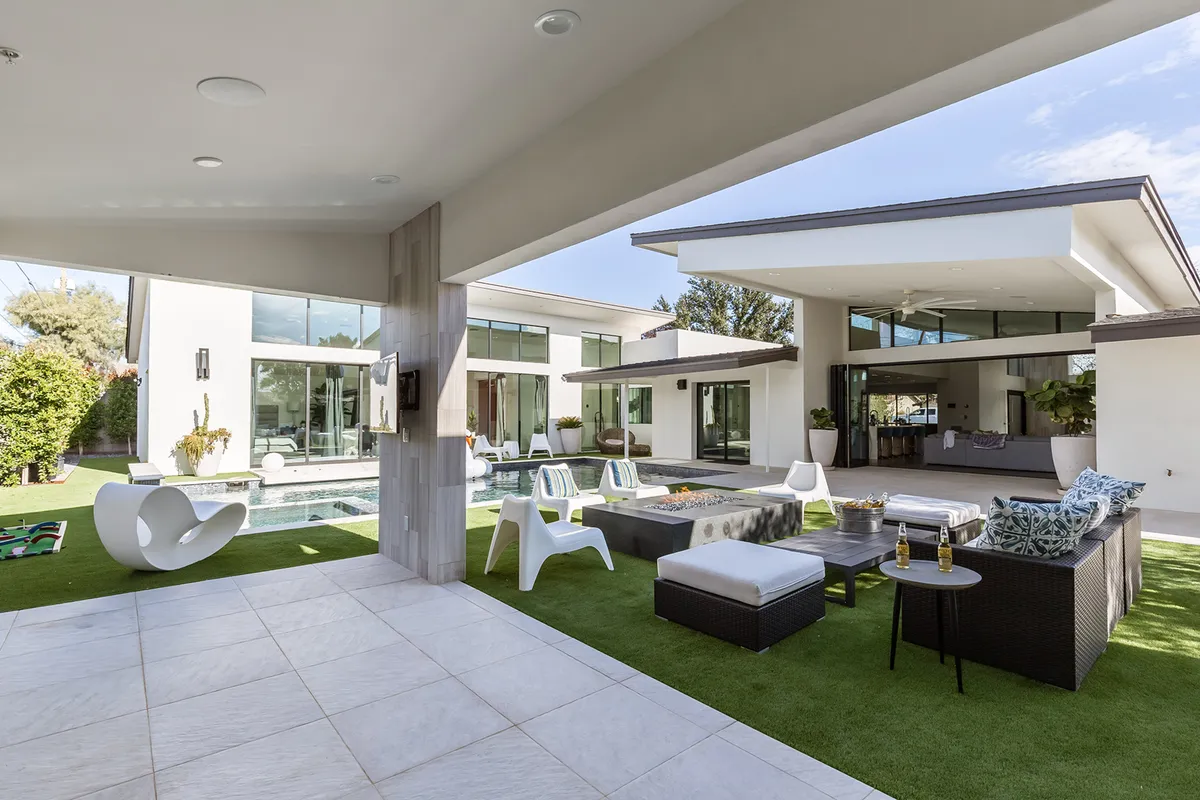 A stylish swimming pool scene with an outdoor seating area, modern sculptures, and a landscaped garden, perfect for relaxing, entertaining friends, or enjoying festive poolside moments under the stars.