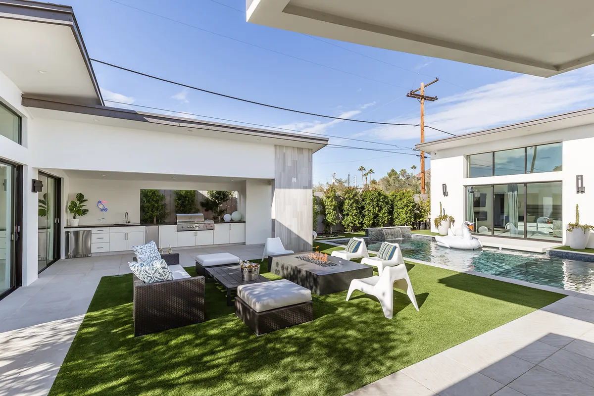 This cheerful outdoor space showcases an inviting swimming pool, an outdoor kitchen, and a lounging area. The scene exudes a casual, summery vibe, ideal for dining, swimming, and social celebrations.