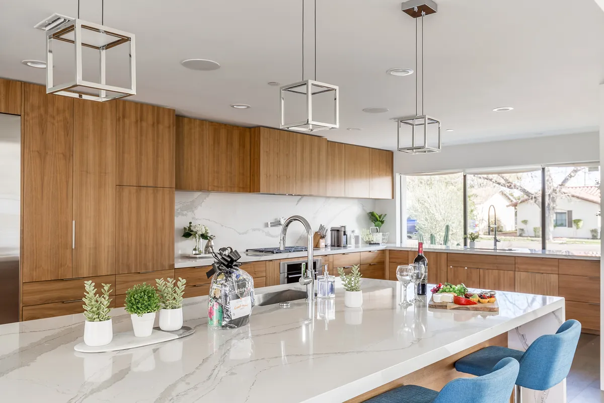 A sophisticated kitchen scene focused on the kitchen island with hanging light fixtures, custom cabinetry, and a window view. The image highlights the high-end finishes, modern appliances, and design details ideal for culinary creativity and gatherings.